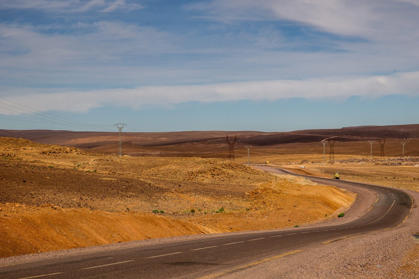 high angle shot of a highway surrounded by sandy hills with power stations