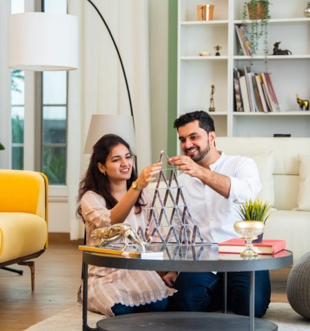 Indian asian young couple building a house using playing cards and having fun