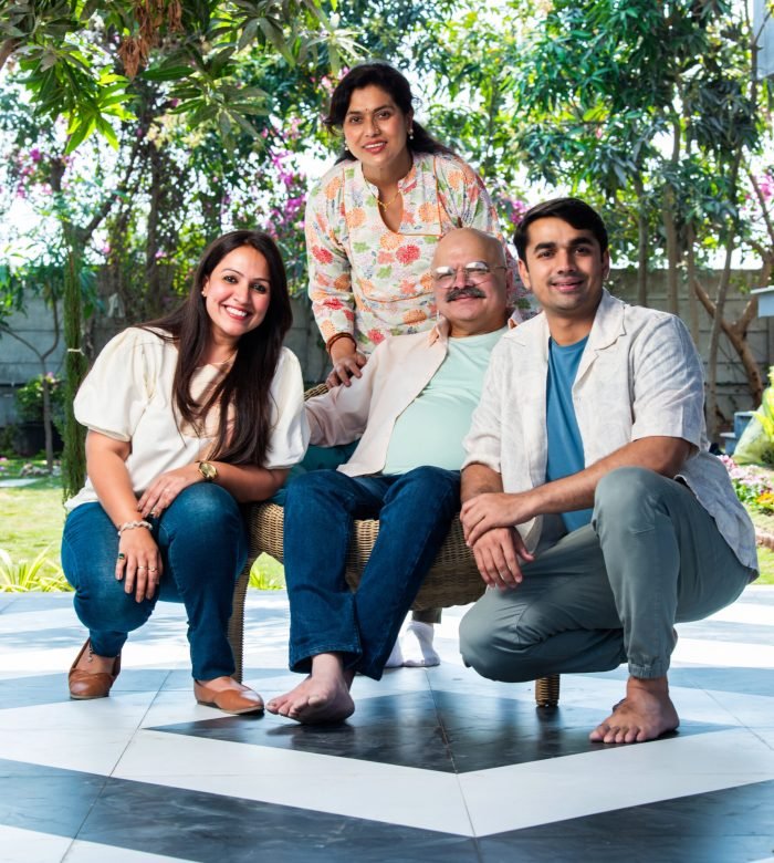 Portrait of happy Indian family of four sitting outdoor on stairs looking at camera